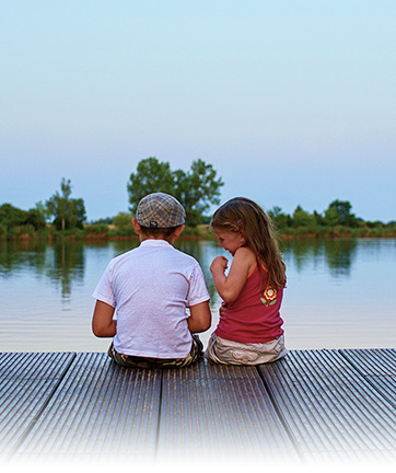 Dos niños sentados frente a un lago