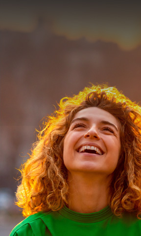 Mujer jóven sonriendo y mirando al cielo.