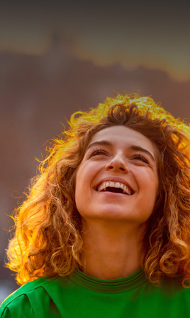 Mujer jóven sonriendo y mirando al cielo.