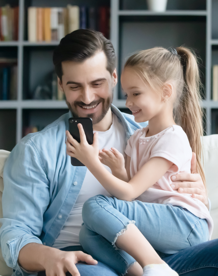 Dad and his daugther looking at the mobile phone.