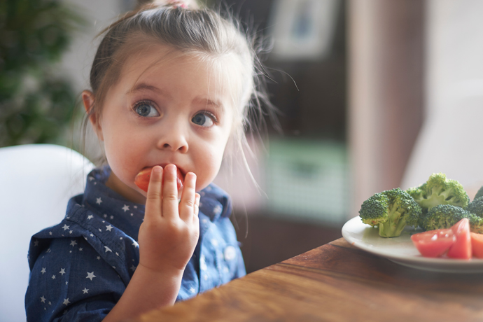 Niña comiendo un tomate de su ensalada