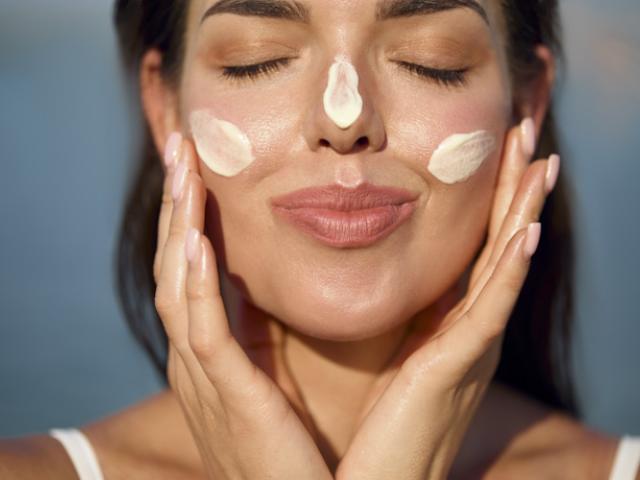Mujer aplicando protector solar, medida para prevenir el cáncer de piel 