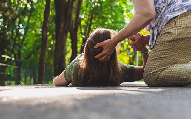 Mujer en el suelo siendo asistida por otra persona.