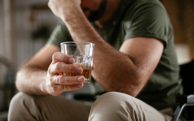 Hombre sujetando un vaso con licor