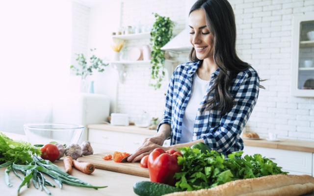 Mujer prepara comida con alimentos anticancerígenos