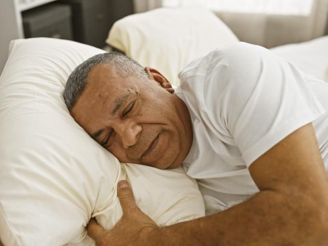 Hombre ecuatoriano descansando plácidamente en su cama para ilustrar la importancia de una buena higiene del sueño en Ecuador.