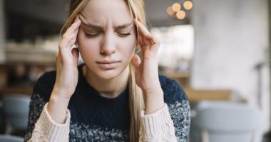 Mujer joven con migraña intensa sosteniendo su cabeza por el dolor.