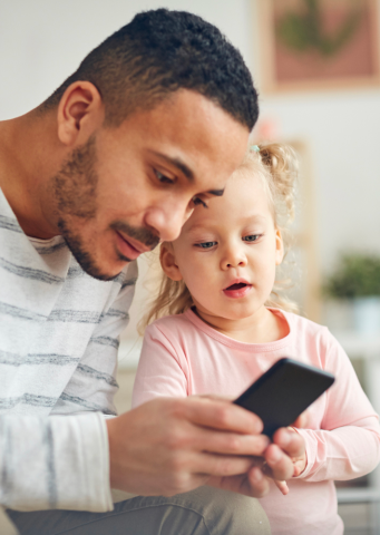 Papá con su hija viendo su celular.