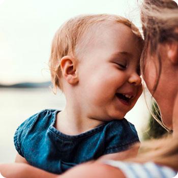 Bebé sonriendo en los brazos de su mamá.